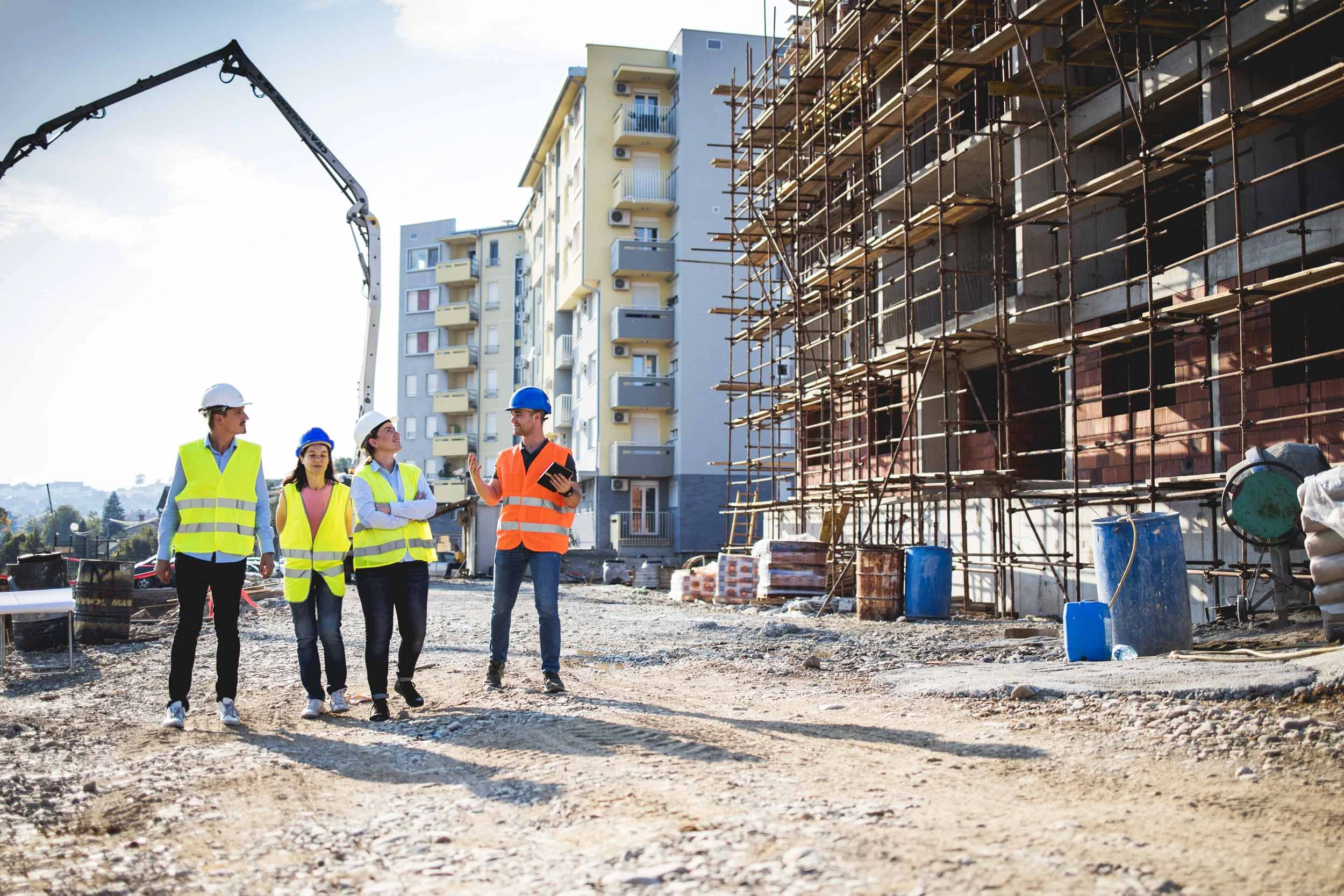 Four construction workers on a construction sit discussing the works with site supervisor in an orange hi vis vest