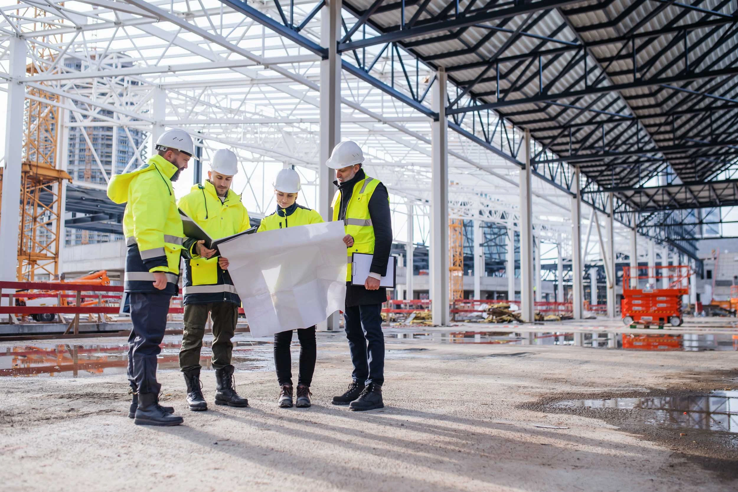 Senior construction workers on site wearing PPE and holding site plans