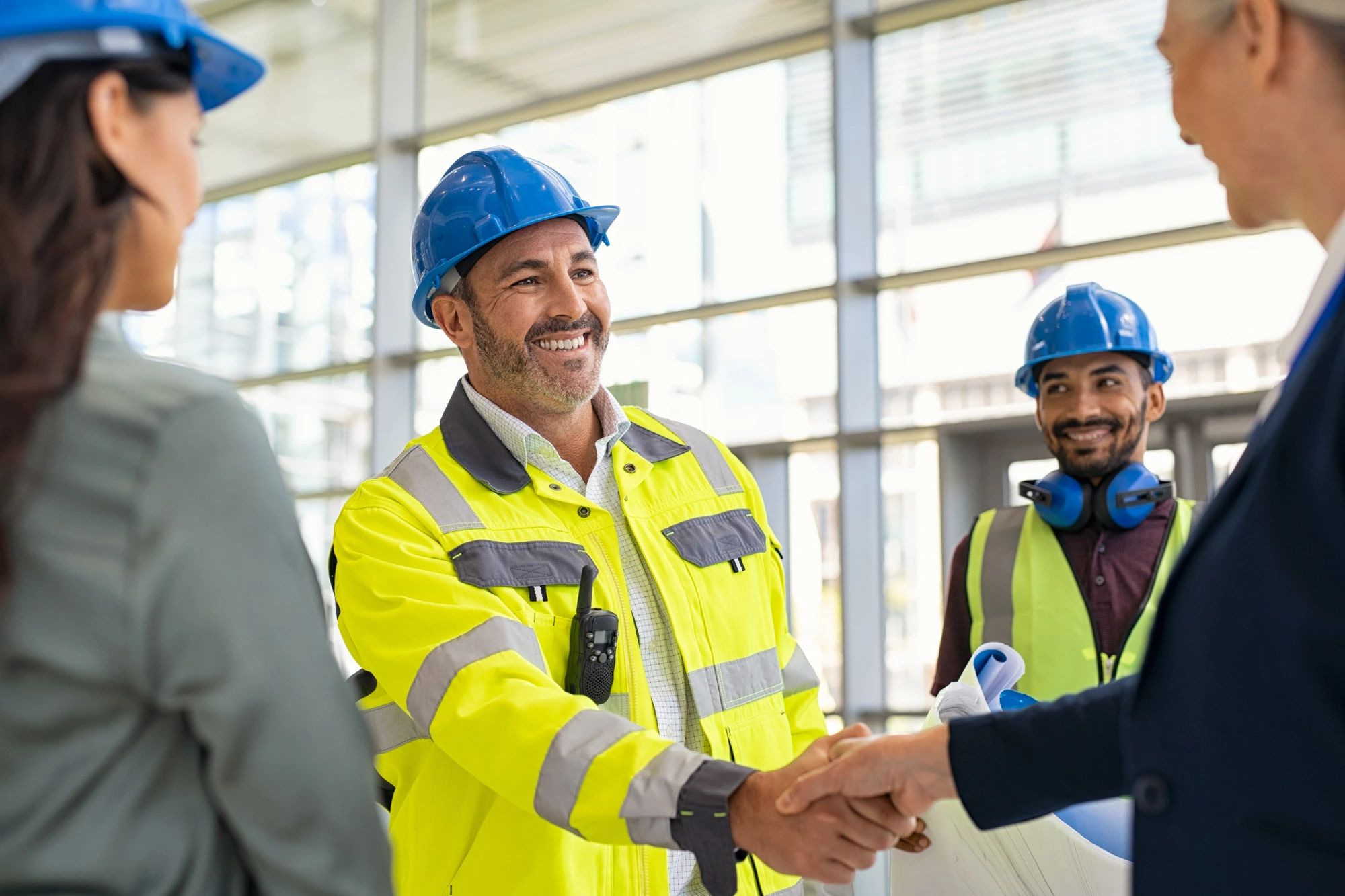 Senior construction workers on site shaking hands wearing PPE shaking hands