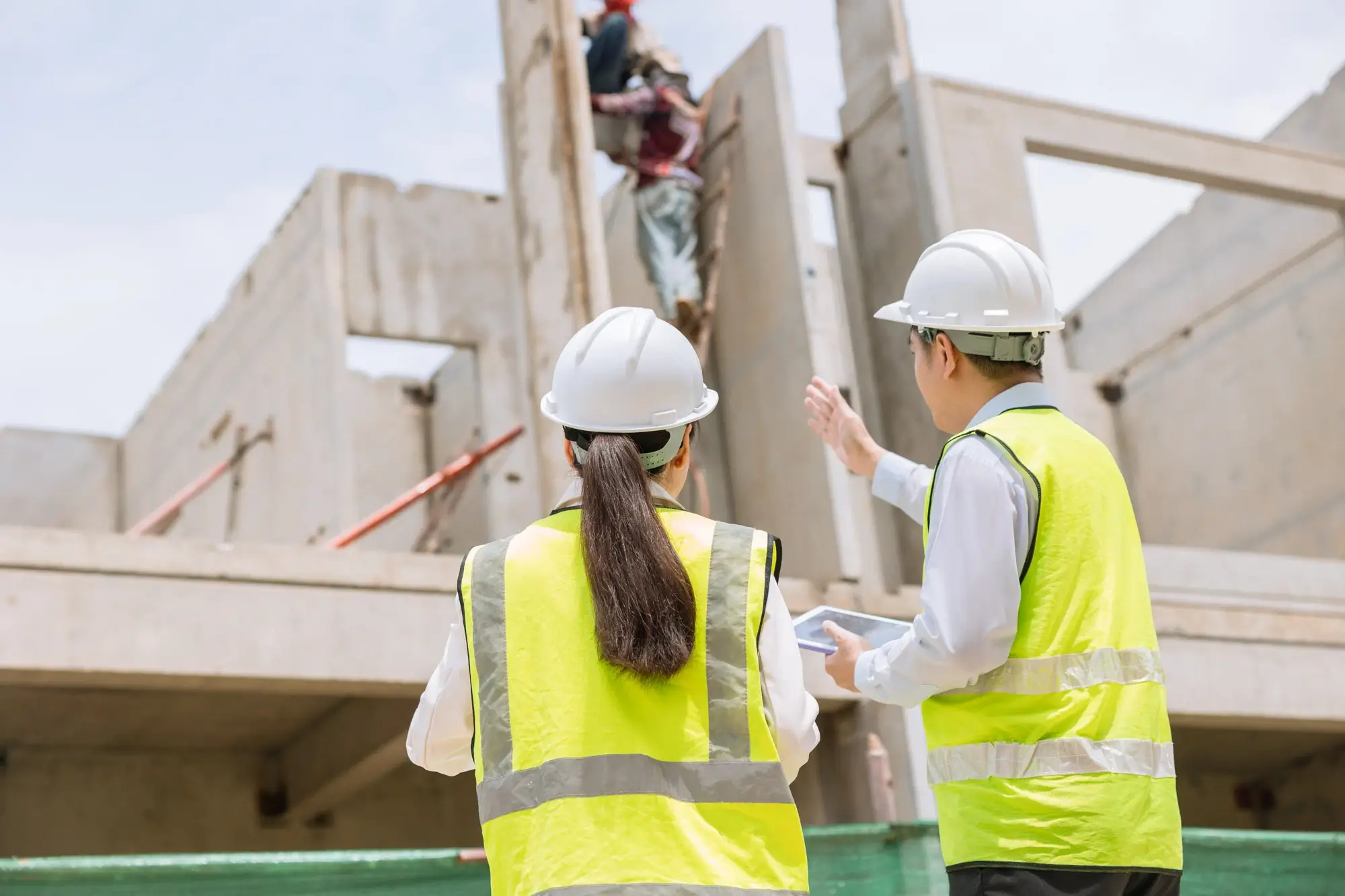 Construction senior worker assessing work on site with younger construction female worker