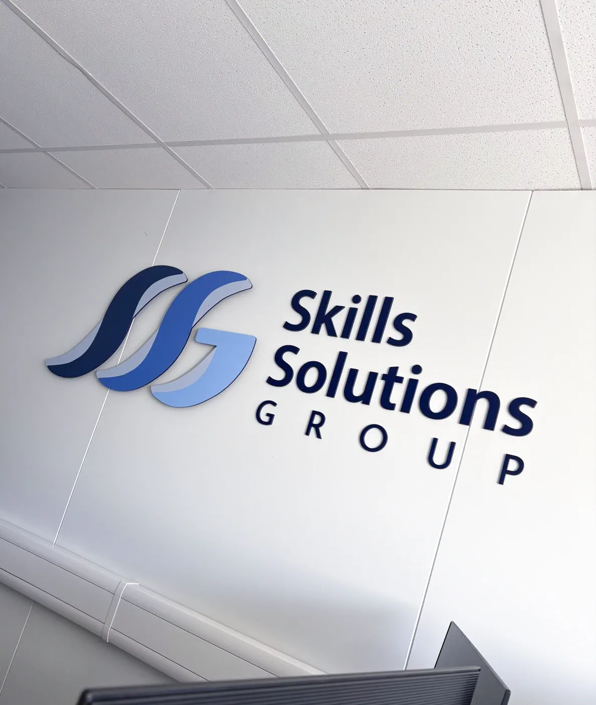 New Skills Solutions Group office signage celebrating company and quality assurance milestones